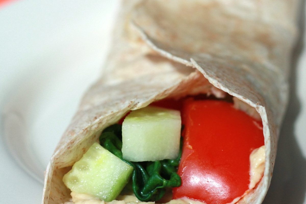 Vegetable hummus wrap cut in half on a plate